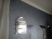 Wohnzimmerwand mit einer strukturierten Vliestapete tapeziert und in Silber gestrichen
